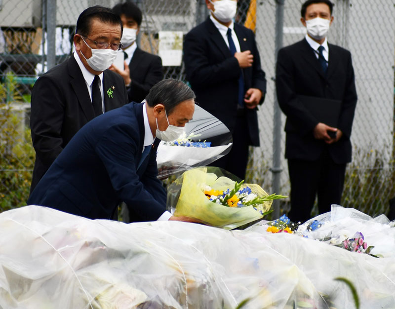 児童５人が死傷した事故で、事故現場を訪れ花を手向ける菅義偉首相（当時）＝昨年７月、八街市