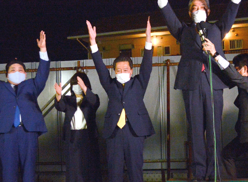 八千代市長に再選され、支援者らと万歳に臨む服部友則氏(中央)=23日夜、八千代市内の報告会場