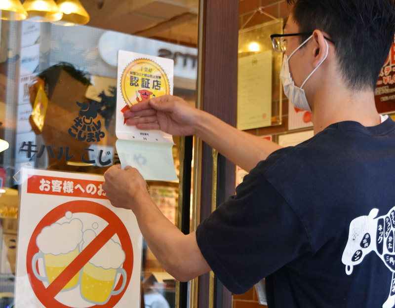 認証店のステッカーを貼る「牛バル こじまや 千葉店」の店員=28日午後1時40分ごろ、千葉市中央区