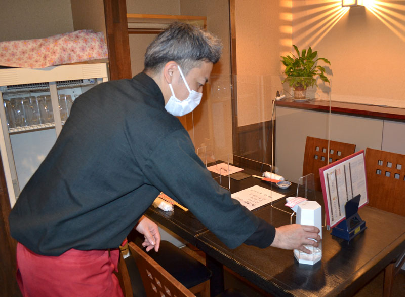 客席に消毒液を設置する根岸さん。重点措置解除で客足の回復に期待を寄せる=15日午後3時半ごろ、千葉市中央区