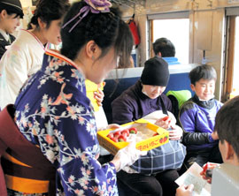 デゴイチの車内で乗客に東庄町名産のイチゴ「アイベリー」を配る女性職員=30日