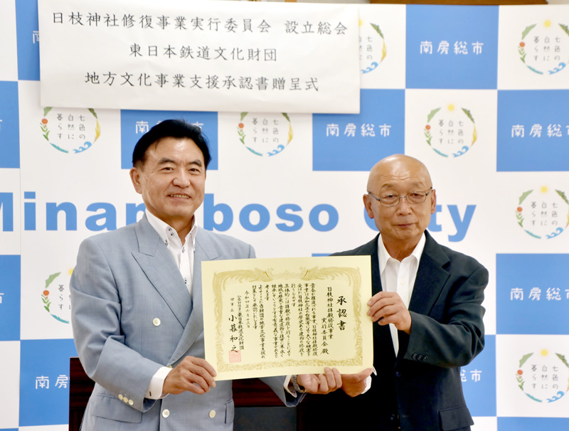 支援承認書を掲げる日枝神社拝殿修復事業実行委の国府田会長(右)と東日本鉄道文化財団の太田専務理事