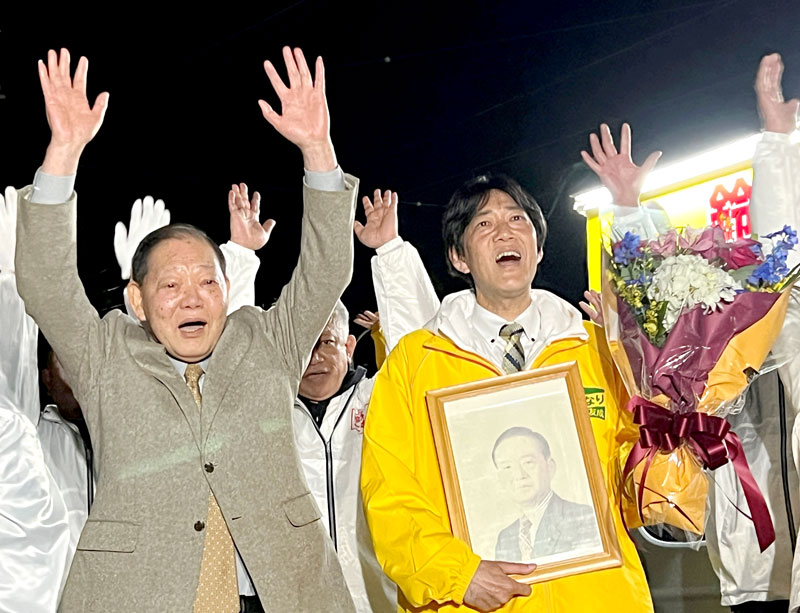 喜ぶ鈴木友成氏（右）と、引退する父の昌俊県議。遺影は市議を務めた祖父の故・日定氏＝９日午後１０時５５分ごろ、市原市