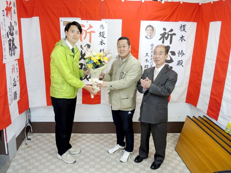当選を決めた後、支援者から花束を渡される榎本氏（左）＝１０日午前１時１０分、野田市