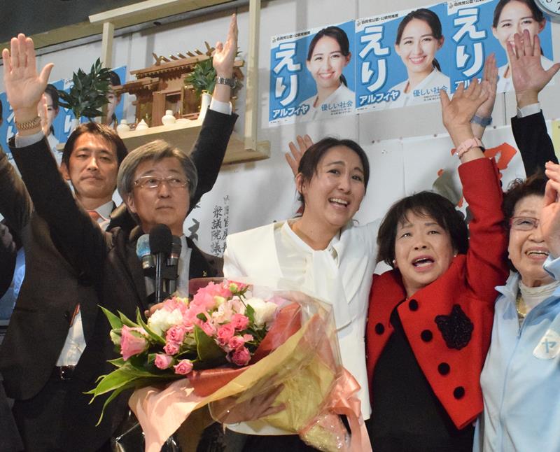 衆院千葉５区補選で初当選を決め、万歳する自民の英利氏（中央）＝２４日午前０時２０分ごろ、市川市