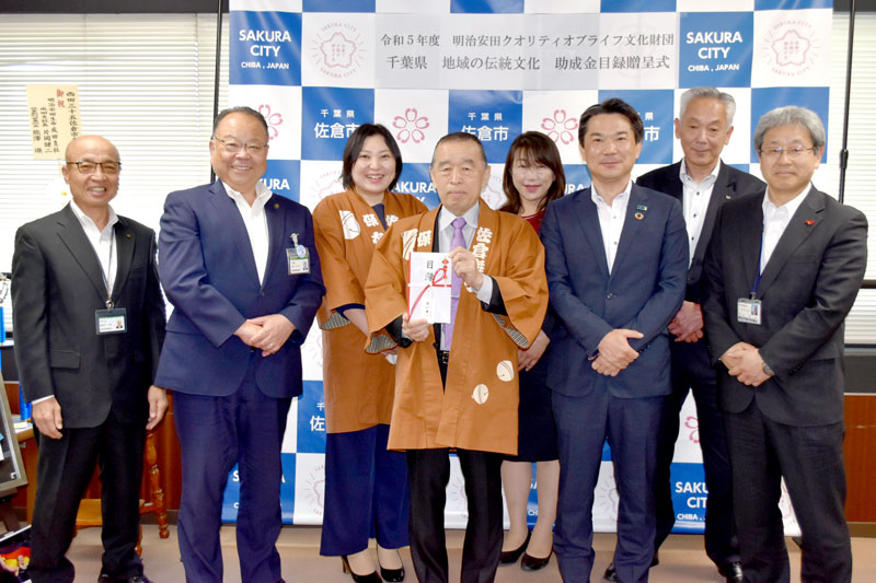 目録を手渡した明治安田生命成田支社の片岡支社長（前列右から２人目）や、佐倉囃子保存会の平野会長（同中央）ら＝佐倉市役所