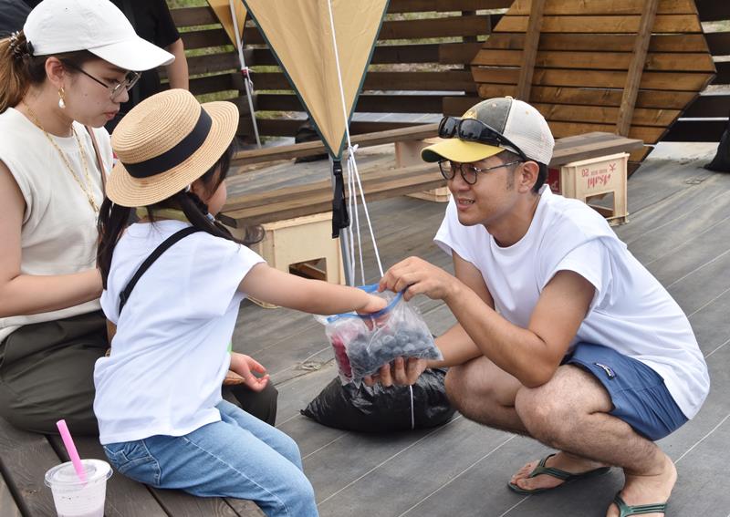 冷凍したブルーベリーを配る宇部さん（右）