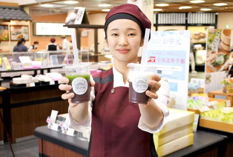 和菓子が多く陳列された米屋の総本店の中で食べ歩き商品「まぜよ~かん」を紹介するスタッフ=成田市