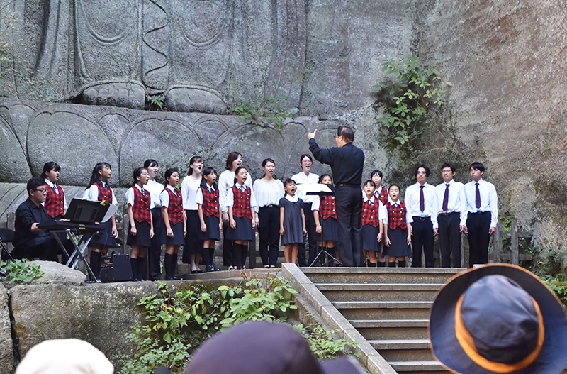 百尺観音の前で美声を響かせる鴨川少年少女合唱団=30日、鋸南町