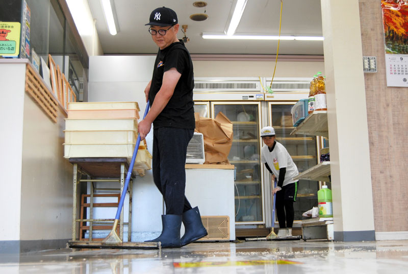 店内に入り込んだ泥水をかき出す男性ら=9日午前10時40分ごろ、長柄町鴇谷