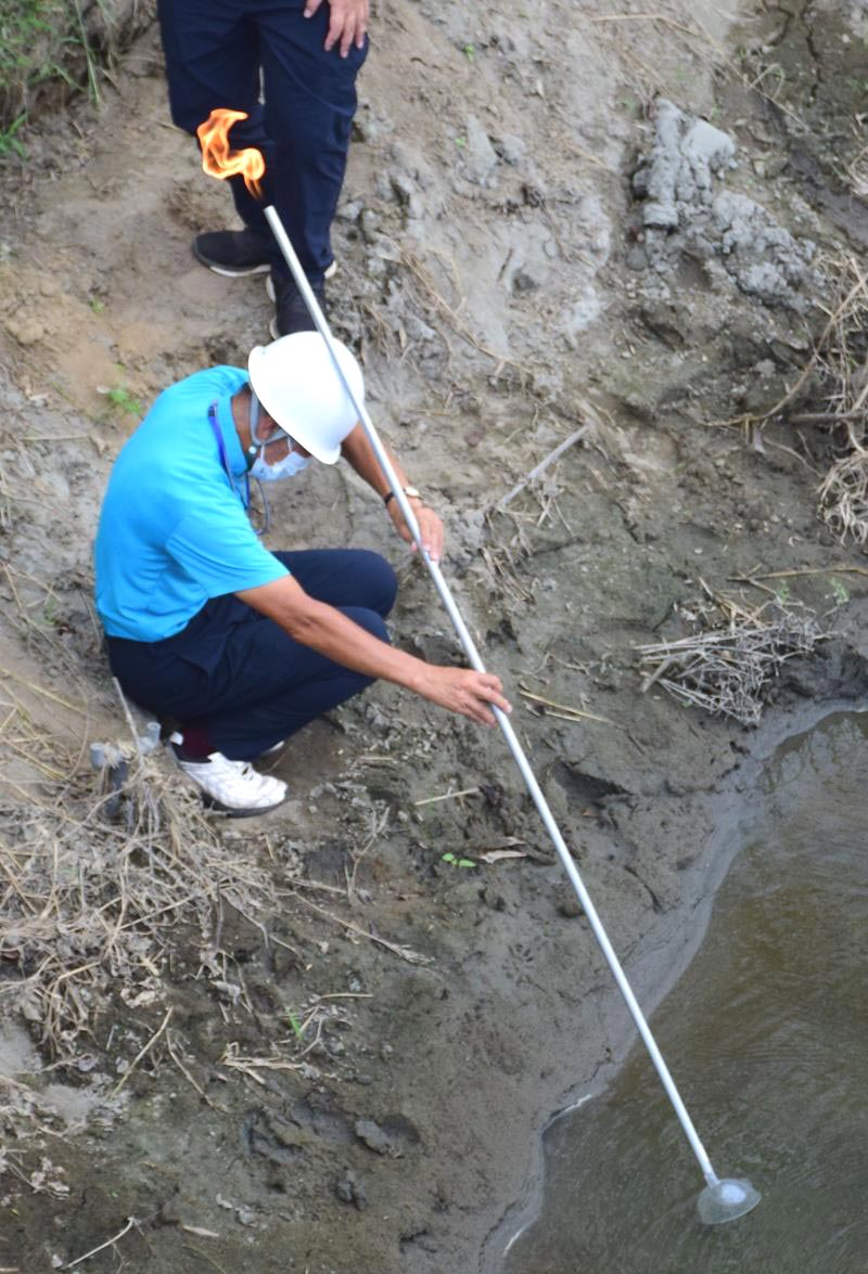 川底から吹き出る天然ガスを集め火を付ける実行委メンバー=睦沢町