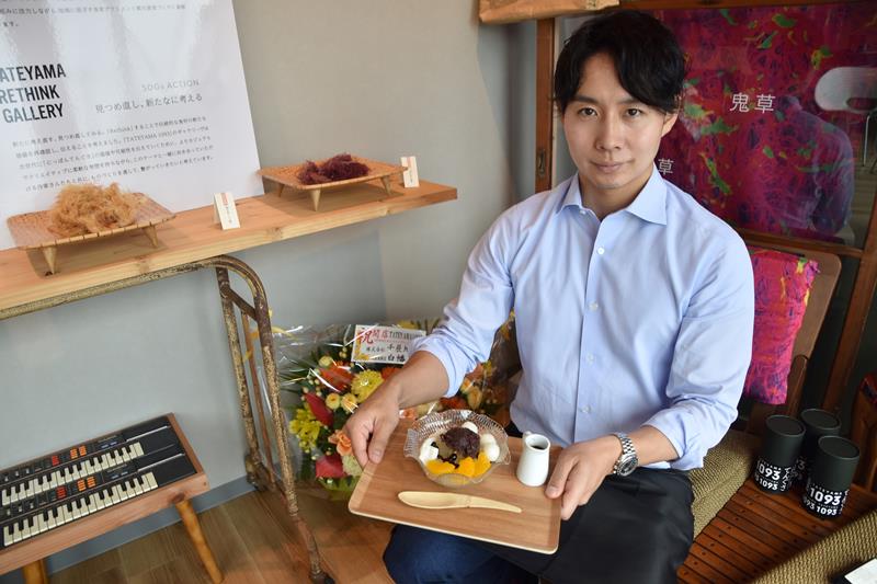 館山産天草100%の寒天を入れた特製あんみつを手に持つ小形社長=館山市