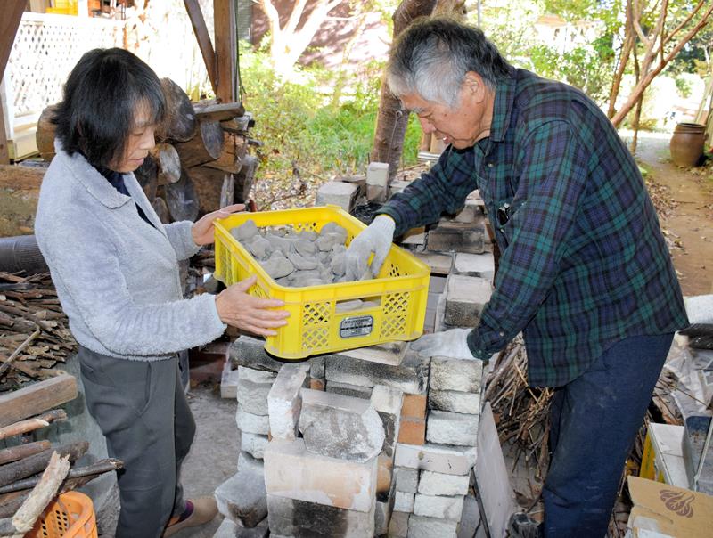 乾燥させた芝原人形を窯に入れる千葉惣次さん(右)と真理子さん=11月29日、長南町