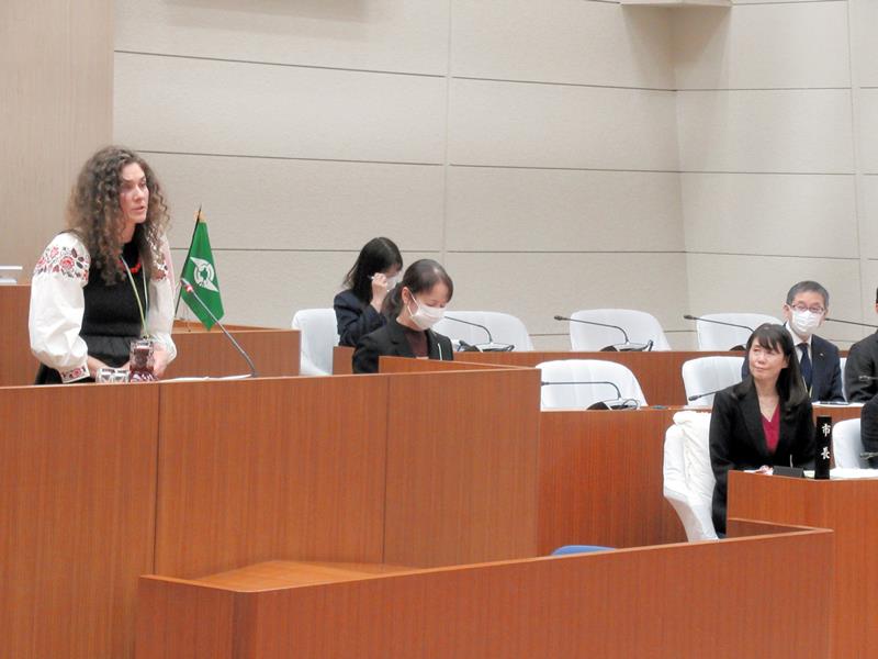 議場でスピーチするナセドキナさん(左)。右前列は芝田市長=11月30日、鎌ケ谷市
