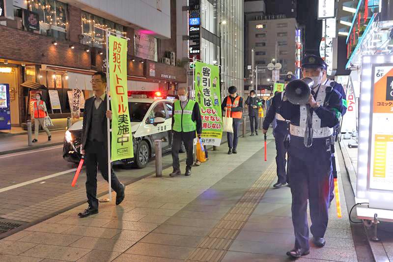 メガホンで通行人に「客引きは違法行為」と呼びかける警察官=11月24日、千葉市中央区