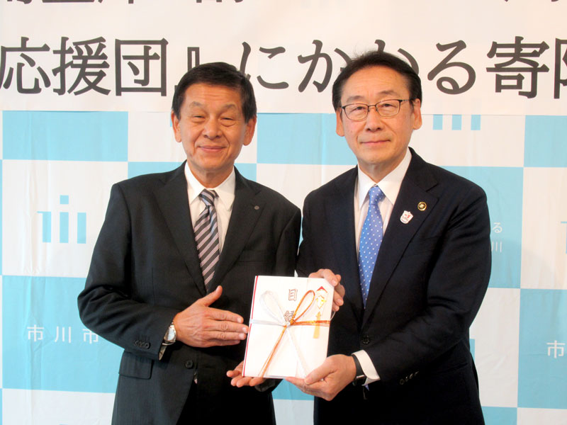 １千万円の目録を田中市長（右）に渡す伊藤理事長＝市川市役所