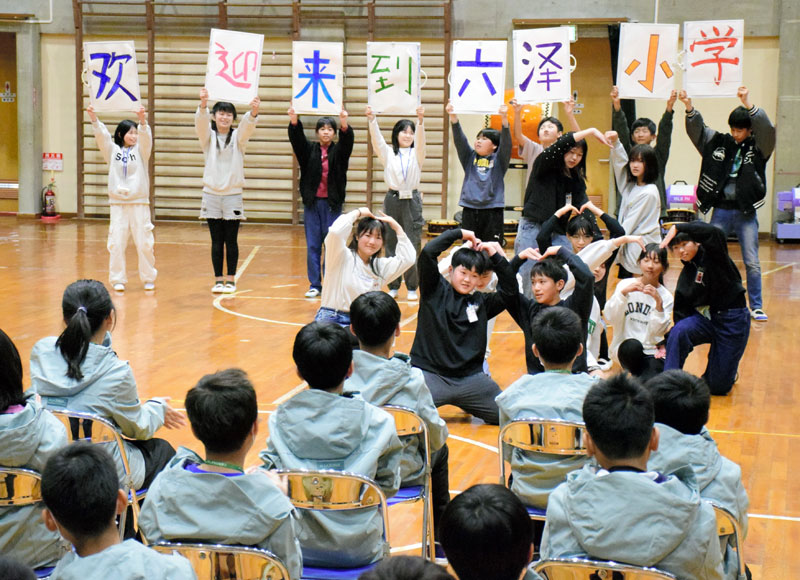 台湾児童(手前)の来校を歓迎するボードを掲げる睦沢小の児童=19日、睦沢町