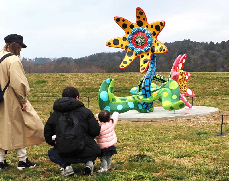 草間弥生さんの「明日咲く花」。クルックフィールズを訪れた家族連れが展示作品に見入った=23日、木更津市