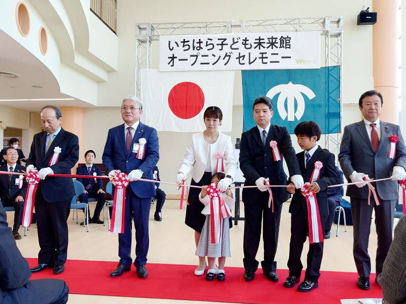 いちはら子ども未来館(愛称=weほーる)のオープニングセレモニーで、テープカットに臨む小出市長(手前左から2人目)と愛称考案者の品田さん(中央)ら