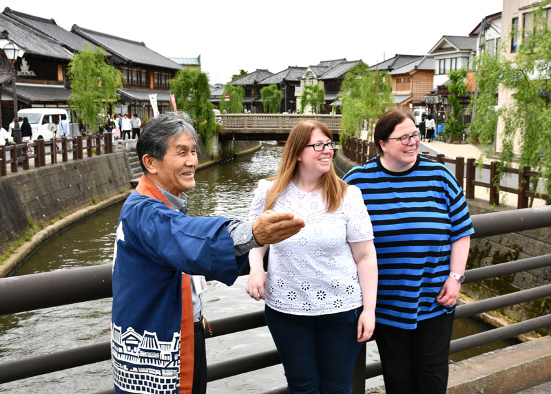 佐原の町並みを訪れた外国人観光客を案内する高谷館長(左)=香取市