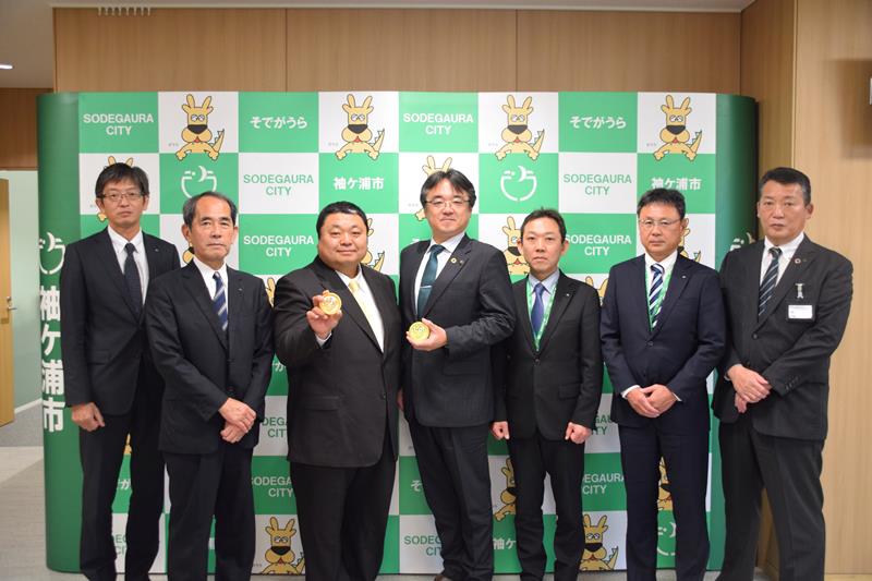 とうもろこしアイスを持つ斎藤社長(左から3人目)と粕谷市長(同4人目)=袖ケ浦市