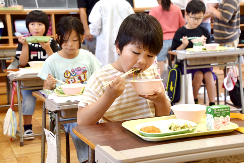 県産ダイコンなどが入ったみそ汁を頬張る西岬小児童＝１４日、館山市