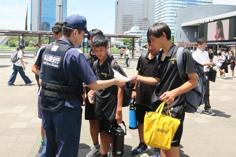 水難事故防止の啓発リーフレットを受け取る学生ら=19日、千葉市美浜区のJR海浜幕張駅前