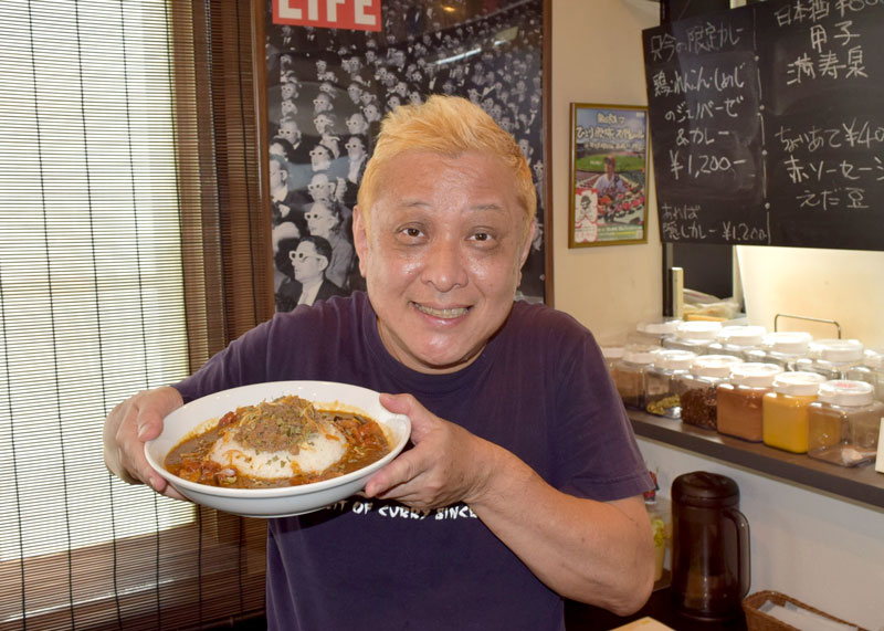 和キーマと野菜をトッピングした一押しカレーを手にする飯村さん=習志野市