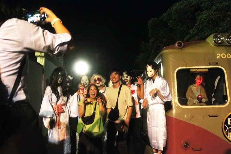 お化け屋敷電車のゾンビや濡女に囲まれ撮影する参加者＝銚子電鉄犬吠駅