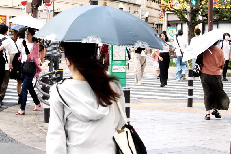 強い日差しの中、日傘を差して歩く人たち=14日午後、千葉市中央区