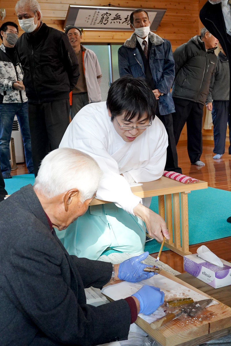 竹筒を割って中身の具合を確認する松山宮司(中央)と地元住民ら=15日、匝瑳市