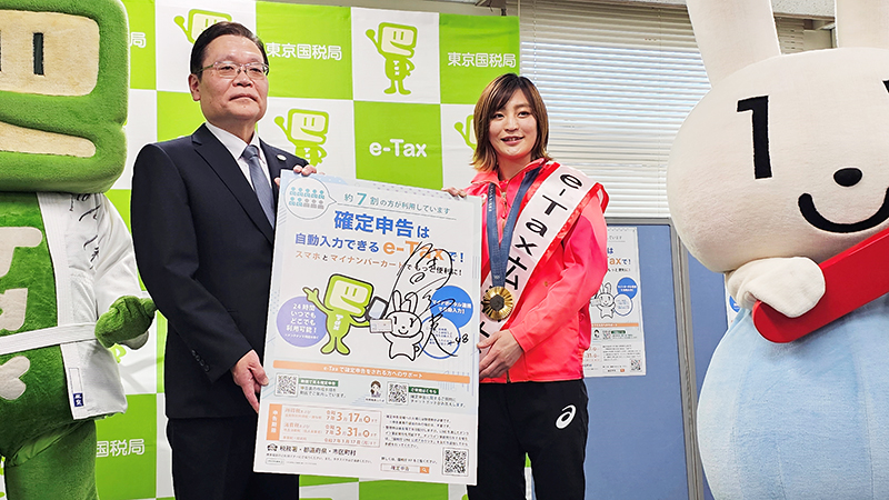ポスターを手に「e-Tax」をPRする角田選手(右)=30日、千葉市花見川区の千葉西税務署