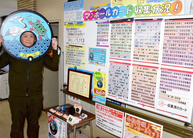 マンホールカードの収集状況を紹介するボード。収集済には「済」のシールが貼られている。長生村のご当地マンホールふたの顔はめパネルも作った=同村役場