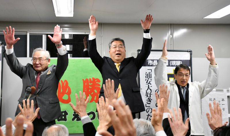 浦安市長選で無投票３選を決め、万歳する内田氏（中央）＝９日、浦安市