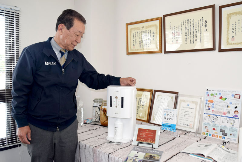 スーパーアルカリイオン水の家庭用小型生成機の機能を説明する松沢社長=船橋市