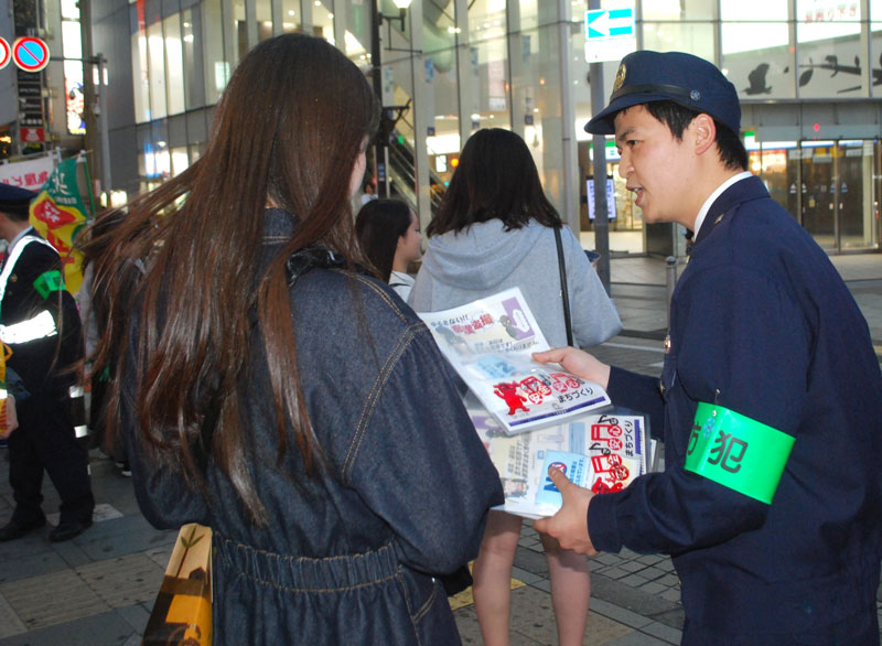 性犯罪などへの注意喚起チラシを手渡す千葉中央署員＝１８日夕、千葉市中央区富士見