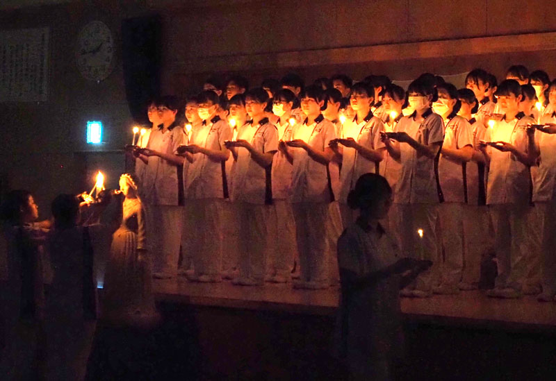 ナイチンゲール像の前でキャンドルに点灯し、壇上に整列する看護学生＝２日、木更津市