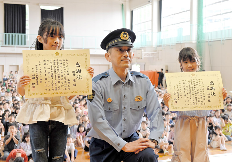 迷子の女の子を助け、全校児童の前で感謝状を受け取った渋井さん(左)と伊藤さん(右)=14日、八千代市緑が丘の市立新木戸小学校